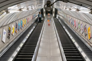 Londra, İngiltere - 8 Haziran 2020: COVID-19 salgını sırasında sosyal uzaklık ölçümlerini izleyen maske takan bir adamla Londra metro yürüyen merdiveni