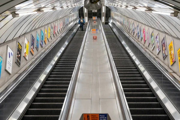 Londra 8 Haziran 2020 'de, COVID-19 salgını sırasında sosyal mesafeyi ölçen maske takan genç bir Afro-Karayipli kadınla Londra metro yürüyen merdiveni - 019