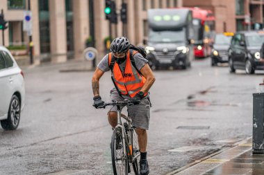Londra, Holborn 'da yağmurlu bir günde COVID-19 salgını sırasında yağmurda boğuşurken yakalanan ve maske takan bisikletçi 10 Haziran 2020