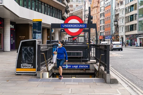 Londra, İngiltere - 24 Temmuz 2020: Chancery Lane Metro İstasyonu 'ndan maske takarak çıkan ve COVID 19 Coronavirus salgını sırasında alışveriş yapan genç Asyalı kadın - 033