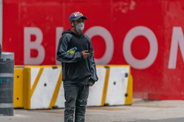 LONDON, ENGLAND - 3 Haziran 2020: Genç Afro-Karayipler Coronavirus COVID-19 pandemik tecrit sırasında yüz maskesi ve beyzbol şapkası takarak Farringdon, Londra, İngiltere 'de yürüyüş - 076