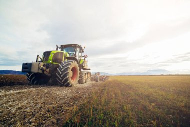 Tarım. Traktör toprağı ekme ve ekip biçme için hazırlıyor. Tarım, çiftçilik kavramı. Tarlalar için tarım makineleri, tarla sürme işi. Yeni modern traktör.