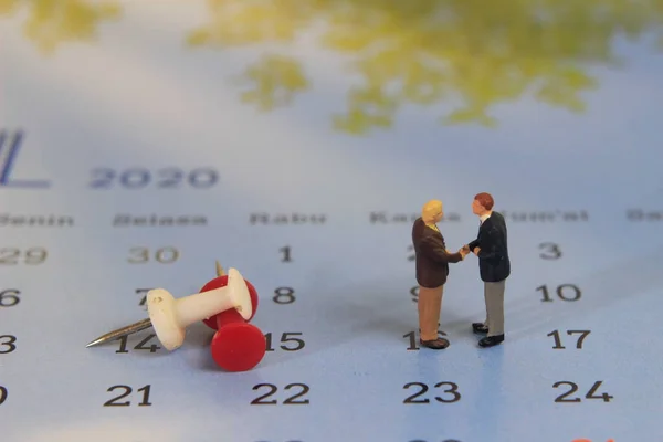 Basit Çizim Fotoğrafı, İki Adam Tokalaşması, Takvim 'de kırmızı ve beyaz rozetin yanında iş anlaşması