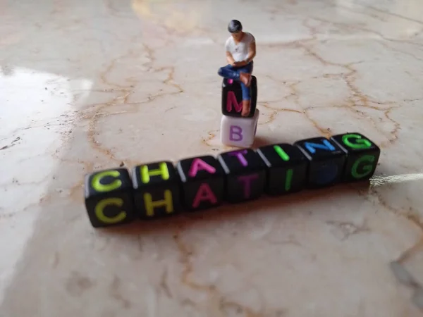 Photo Illustration for Chatting, Mini Figure Toy Sitting at alphabet plastic cube bead