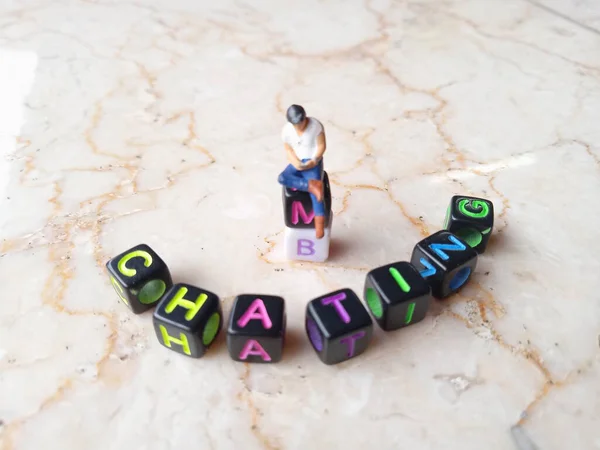 Photo Illustration for Chatting, Mini Figure Toy Sitting at alphabet plastic cube bead