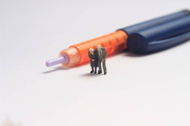 Fotoğraf Yürüyen Mini Oyuncak Beyaz Arkaplanda İnsülin Kaleminin Ötesinde Oturuyor