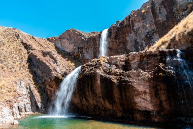 Peru, Marcapomacocha 'da iki katlı çarpıcı bir şelale dramatik kayalık uçurumların üzerinden turkuaz bir havuza akıyor. Dağlık arazi manzarasıyla çevrelenmiş And Dağları 'nın doğal güzelliğini ve eko-turizmini temsil eder..