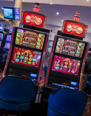 Lima, Peru, 31 Ağustos 2023: Bir kumarhanenin içinde renkli makaralar ve büyük ikramiye ödülleri gösteren neon ışıklarla aydınlatılmış iki modern slot makinesi. Hayat dolu atmosfer kumar, şans ve eğlence kültürünü yansıtıyor..