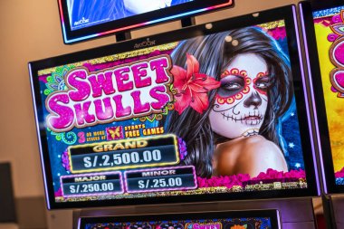 Lima, Peru, 22 Eylül 2023: Ölüler Günü kutlamasından esinlenerek, kafatası makyajlı bir kadının yer aldığı Sweet Skulls slot makinesinin yakın çekimi. Görüntü kumar, kültür, risk, şans ve canlı kumarhane yaşam tarzını temsil ediyor..