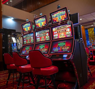 Lima, Peru, 30 Eylül 2023: Parlak kumar makineleri, neon ışıkları ve kırmızı sandalyeleri olan bir kumarhanenin içi. Renkli dijital ekranlar, heyecan, lüks ve oyun eğlencesi dolu canlı bir atmosfer yaratıyor..