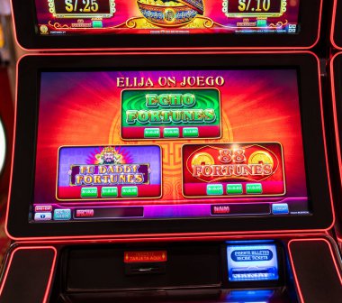 Lima, Peru, 30 Eylül 2023: Modern bir kumarhanede kumar oynayarak renkli servet oyunları sergileyen bir kumar makinesinin dijital ekranı. Parlak neon ışıklar şans ve eğlence dolu oyun atmosferini vurgular.