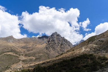 Peru, Cusco 'nun And Dağları' ndaki engebeli dağ zirvesi dramatik bulutlarla dolu mavi bir gökyüzünün altında. Bu doğal manzara, yürüyüşçüler ve maceracılar için popüler bir yer olan Salkantay yürüyüş rotasının bir parçasıdır..