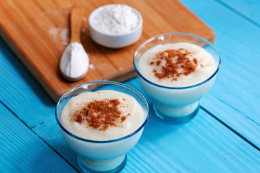 Tarçınlı ev yapımı Türk kreması, ahşap arka planda Türk muhallebi