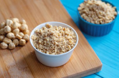 Ahşap arka planda bir kase doğranmış fındık