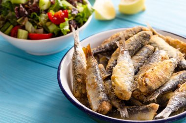 Limonlu kızarmış sardalya ve ahşap arka planda salata.