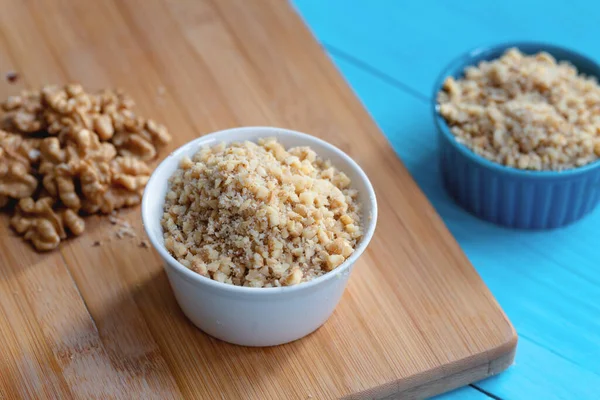 Ahşap arka planda bir kase doğranmış ceviz.