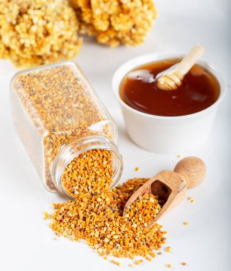 Beyaz arka planda arı poleni ve bal var..