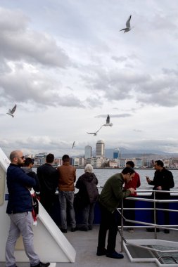İzmir / Türkiye - 12 / 18 / 2017: Karsiyaka 'ya giden bir yolcu feribotunda. İnsanlar denizi ve martıları izliyor.. 