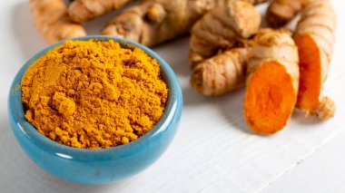 Yiyecek ve içecek, diyet beslenme, sağlık konsepti. Çiğ organik turuncu zerdeçal kökü ve toz, grunge yemek masasında sokağa çıkma yasağı. Hint asıllı düşük kolesterol baharatları