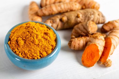 Yiyecek ve içecek, diyet beslenme, sağlık konsepti. Çiğ organik turuncu zerdeçal kökü ve toz, grunge yemek masasında sokağa çıkma yasağı. Hint asıllı düşük kolesterol baharatları