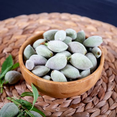 Beyaz arka planda ahşap bir kasede taze yeşil badem..