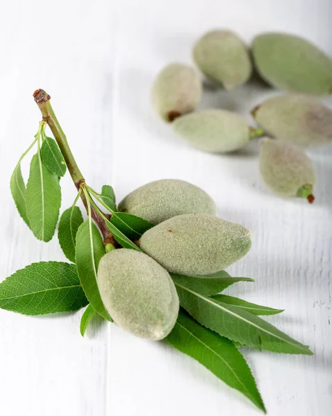 Fresh green almonds in a wooden bowl on white background.