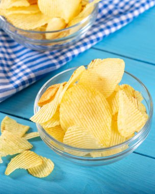 Tahta arka planda cam kasede patates cipsi..