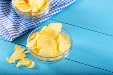 Tahta arka planda cam kasede patates cipsi..