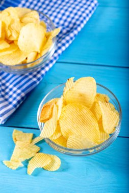 Tahta arka planda cam kasede patates cipsi..