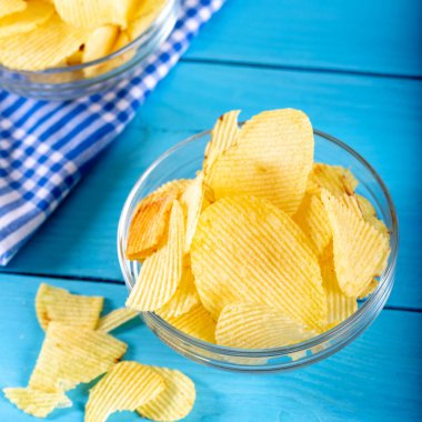 Tahta arka planda cam kasede patates cipsi..