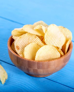 Tahta arka planda tahta kasede patates cipsi..