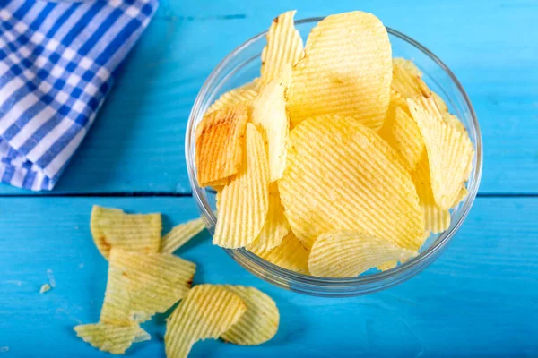 Tahta arka planda cam kasede patates cipsi..