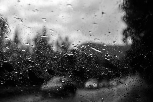 Car window with rain drops. Driving in rain. Weather background. Rainy glass.