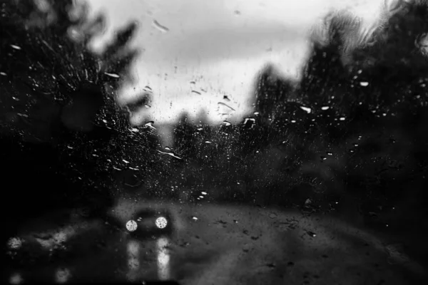 Car window with rain drops. Driving in rain. Weather background. Rainy glass.