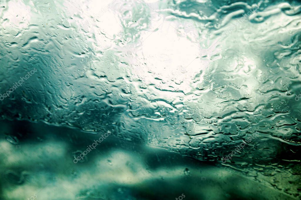 Road view through car window with rain drops. Driving in rain. Selective focus