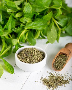 Beyaz bir kasede kurutulmuş nane şekeri ve ahşap zemin üzerinde taze nane. Gıda arkaplanı.