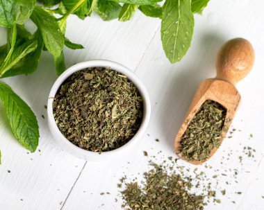 Beyaz bir kasede kurutulmuş nane şekeri ve ahşap zemin üzerinde taze nane. Gıda arkaplanı.