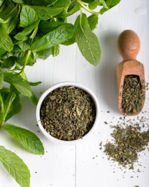 Beyaz bir kasede kurutulmuş nane şekeri ve ahşap zemin üzerinde taze nane. Gıda arkaplanı.