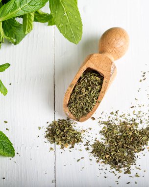 Beyaz bir kasede kurutulmuş nane şekeri ve ahşap zemin üzerinde taze nane. Gıda arkaplanı.