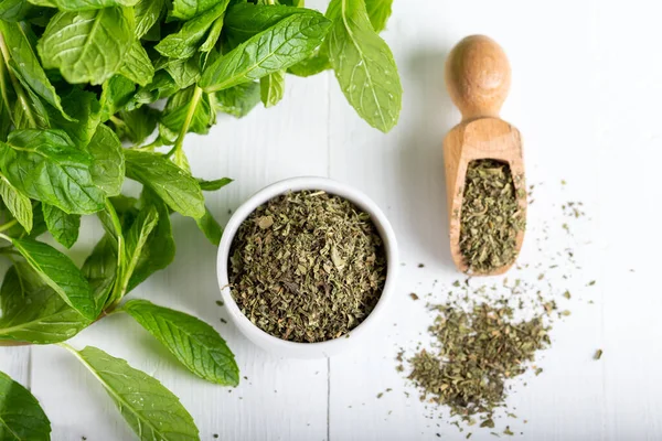 Beyaz bir kasede kurutulmuş nane şekeri ve ahşap zemin üzerinde taze nane. Gıda arkaplanı.