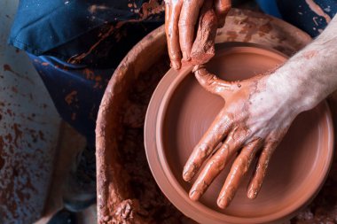 Çömlekçinin elleri çömlek çarkında kil tenceresi yapıyor.