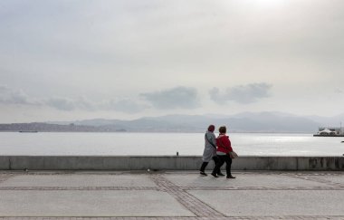 İnsanlar Karsiyaka İzmir kıyı parkı boyunca yürüyor.