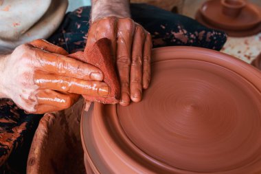 Çömlekçinin elleri çömlek çarkında kil tenceresi yaratıyor..