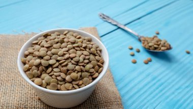 Bir kase yeşil pişmemiş mercimek mavi arka planda kasede..