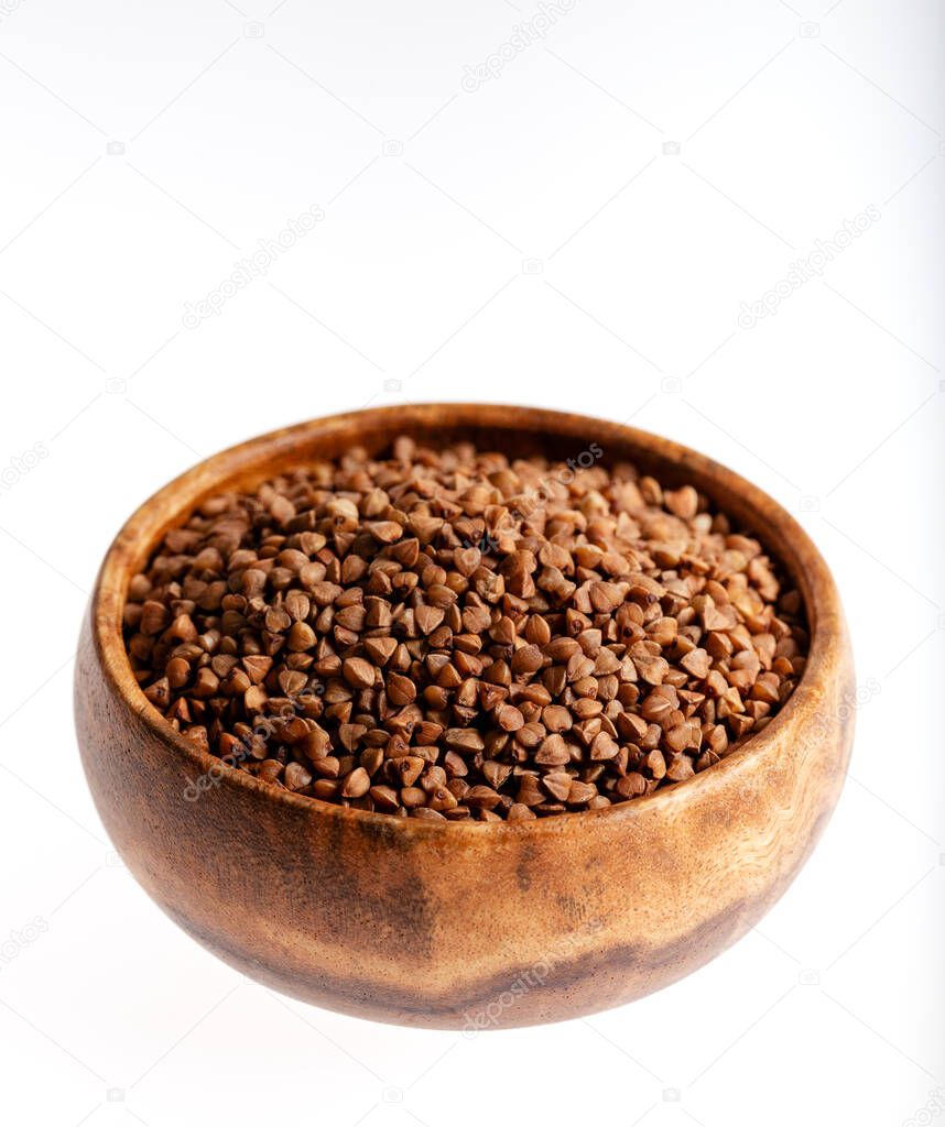 Bowl of raw buckwheat on white background