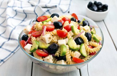 Beyaz arka planda makarna ile Yunan salatası.