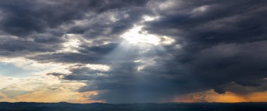 Işık huzmeleri, kara bulutlar boyunca parlıyor. 