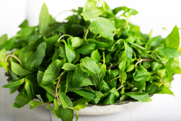 Mint. Bunch of Fresh green organic mint leaf in bowl on wooden table closeup
