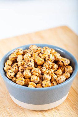 Ahşap arka planda, seramik kasede kavrulmuş, sarı nohut..