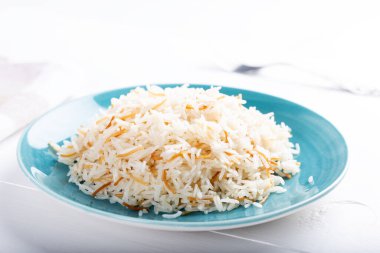 Beyaz arka planda seramik kasede ya da tabakta servis edilen haşlanmış basmati pilavı..